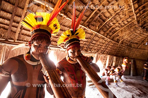  Yawalapiti indians wearing headdresses named tunacape (cocar), playing the Urua flute inside the maloca reserved to men - Casa dos Homens - during the Kuarup ceremony - this years ceremony in honor of the anthropologist Darcy Ribeiro - Photo License  - Gaucha do Norte city - Mato Grosso state (MT) - Brazil