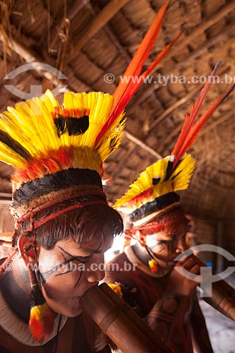  Yawalapiti indians wearing headdresses named tunacape (cocar), playing the Urua flute inside the maloca reserved to men - Casa dos Homens - during the Kuarup ceremony - this years ceremony in honor of the anthropologist Darcy Ribeiro - Photo License  - Gaucha do Norte city - Mato Grosso state (MT) - Brazil