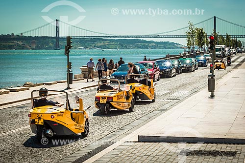  Tourist in GoCAR - system of sightseeing by car guided by GPS - on the baks of Tejo River with the Ponte 25 de abril (April 25 Bridge) in the background  - Lisbon - Lisbon district - Portugal