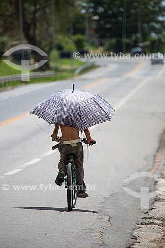  Cyclist with umbrella on the kerbside of Lucio Meira Highway (BR-393) near to KM-177 - Northbound  - Tres Rios city - Rio de Janeiro state (RJ) - Brazil