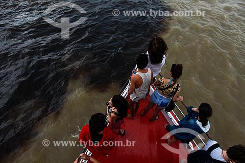  Persons observing the meeting of waters of Negro River and Solimoes River from boat prow  - Manaus city - Amazonas state (AM) - Brazil
