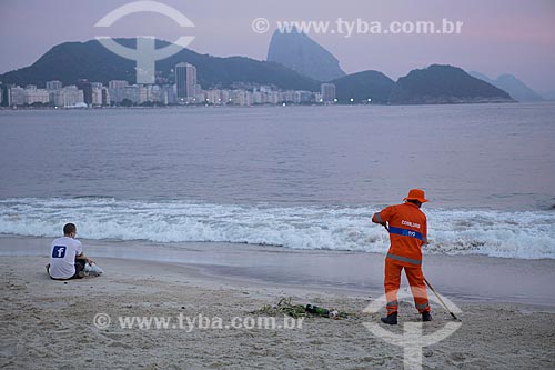  Refuse collector cleaning the Copacabana Beach after the Reveillon party - with the Sugar Loaf in the background  - Rio de Janeiro city - Rio de Janeiro state (RJ) - Brazil