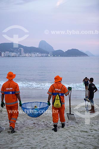  Refuse collectors cleaning the Copacabana Beach after the Reveillon party - with the Sugar Loaf in the background  - Rio de Janeiro city - Rio de Janeiro state (RJ) - Brazil