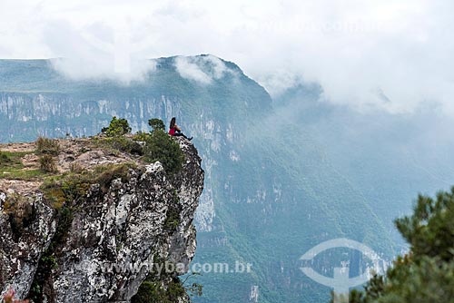 Young woman sitting on the edge of a rock - Fortaleza Canyon - Aparados da Serra National Park  - Cambara do Sul city - Rio Grande do Sul state (RS) - Brazil