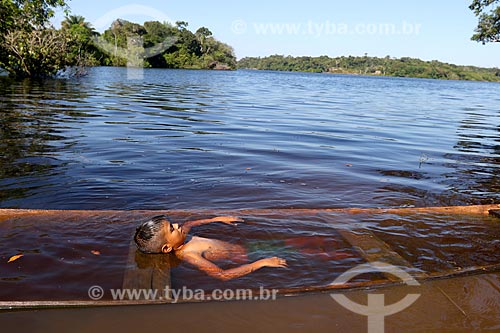  Riverine boy - Tumbira riparian community - playing with canoe almost covered up in Negro River - Anavilhanas National Park  - Novo Airao city - Amazonas state (AM) - Brazil