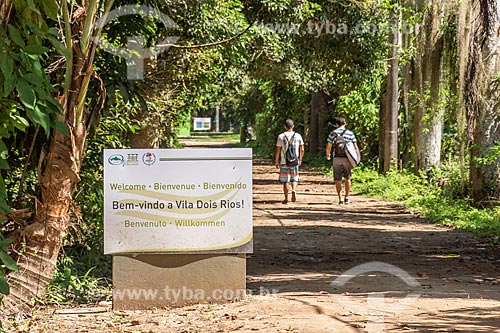  Plaque that says: Welcome to Dois Rios Village with young people in the background walking on the dirt road  - Angra dos Reis city - Rio de Janeiro state (RJ) - Brazil