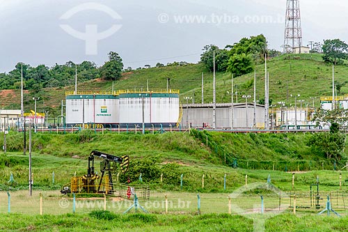  Beam pumping suction - also known as Cavalo de pau (wooden horse) - extracting petroleum urban perimeter of Riachuelo city with tanks in the background  - Riachuelo city - Sergipe state (SE) - Brazil