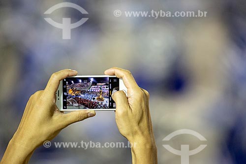  Detail of cell phone photographing the parade of Gremio Recreativo Escola de Samba Unidos de Vila Isabel Samba School - Plot in 2019 - In the name of the Father, the Son and the Saints, the Village sings the city of Peter  - Rio de Janeiro city - Rio de Janeiro state (RJ) - Brazil