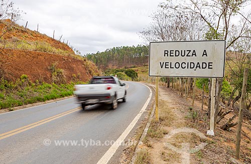  Plaque that says: Reduce speed - kerbside of the MG-353 highway - between Pirauba and Guarani cities  - Guarani city - Minas Gerais state (MG) - Brazil