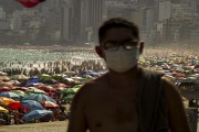 Person wearing protective mask and crowded Ipanema Beach in the background - Coronavirus Crisis - Rio de Janeiro city - Rio de Janeiro state (RJ) - Brazil