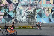 Cyclists with the Ethnicities Wall - Mayor Luiz Paulo Conde Waterfront in the background - Rio de Janeiro city - Rio de Janeiro state (RJ) - Brazil