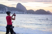 Woman photographing with cell phone the sunrise on Copacabana beach with Sugarloaf Mountain in the background. - Rio de Janeiro city - Rio de Janeiro state (RJ) - Brazil