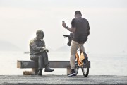 Cyclist with cell phone on the Copacabana Beach boardwalk near the statue of poet Carlos Drummond de Andrade - Rio de Janeiro city - Rio de Janeiro state (RJ) - Brazil