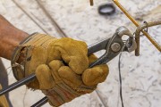 Detail of construction workers hand with glove and using pliers to fix wire to rebar. - Belo Horizonte city - Minas Gerais state (MG) - Brazil
