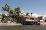 Construction on the edge of the Preguiças River with Preguiças Lighthouse in the background - Barreirinhas city - Maranhao state (MA) - Brazil