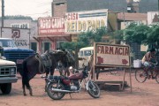 Commercial street with parked cars, horse and motorcycle - The 80s - Rolim de Moura city - Rondonia state (RO) - Brazil
