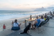 People at bar tables at dusk on Arpoador beach with Two Brothers Mountain in the background - Rio de Janeiro city - Rio de Janeiro state (RJ) - Brazil