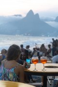 People at bar table using smartphone at dusk on Arpoador beach with Two Brothers Mountain in the background - Rio de Janeiro city - Rio de Janeiro state (RJ) - Brazil