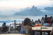 People at bar tables at dusk on Arpoador beach with Two Brothers Mountain in the background - Rio de Janeiro city - Rio de Janeiro state (RJ) - Brazil