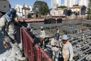 Construction workers wearing mask due to coronavirus pandemic and slab base on shoring in the background - Sao Paulo city - Sao Paulo state (SP) - Brazil