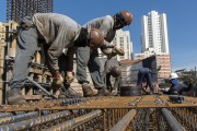 Construction workers assembling iron armor used on pillars and wearing masks due to the coronavirus pandemic - Sao Paulo city - Sao Paulo state (SP) - Brazil