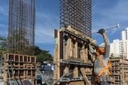 Construction worker nailing wooden box for concreting pillar wearing mask due to coronavirus pandemic - Sao Paulo city - Sao Paulo state (SP) - Brazil