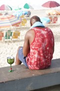 Man sitting on a bench on the Ipanema boardwalk with a glass of drink on the side after New Years eve 2023 - Rio de Janeiro city - Rio de Janeiro state (RJ) - Brazil