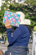 Person protecting face with notebook to avoid being photographed - Rio de Janeiro city - Rio de Janeiro state (RJ) - Brazil