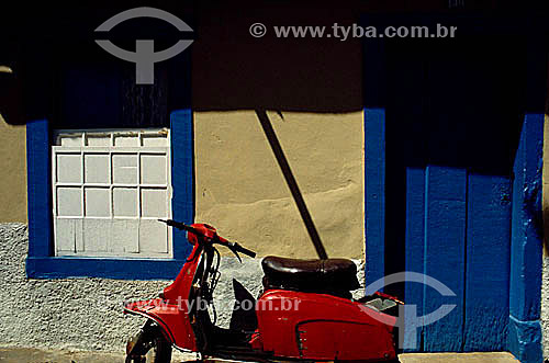  Motocicleta vermelha (vespa) em frente à uma casa de estilo colonial 