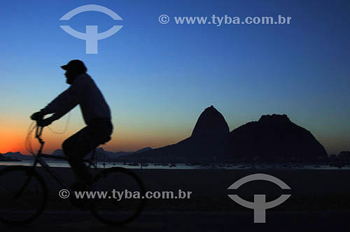  Lazer - silhueta de pessoa andando de bicicleta com o Pão de Açúcar  ao fundo - Praia de Botafogo - Rio de Janeiro - RJ - Brasil

  É comum chamarmos de Pão de Açúcar o conjunto da formação rochosa que inclui o Morro da Urca e o próprio Morro do Pão de Açúcar (o mais alto dos dois). O conjunto rochoso é Patrimônio Histórico Nacional desde 08-08-1973.  - Rio de Janeiro - Rio de Janeiro - Brasil