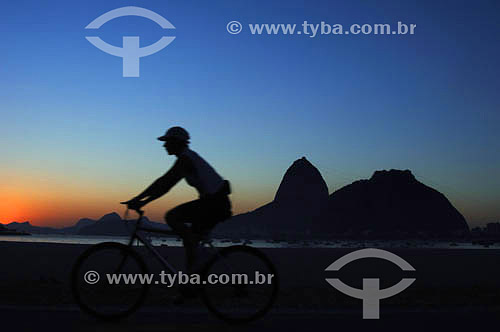  Lazer - silhueta de pessoa andando de bicicleta com o Pão de Açúcar  ao fundo - Praia de Botafogo - Rio de Janeiro - RJ - Brasil

  É comum chamarmos de Pão de Açúcar o conjunto da formação rochosa que inclui o Morro da Urca e o próprio Morro do Pão de Açúcar (o mais alto dos dois). O conjunto rochoso é Patrimônio Histórico Nacional desde 08-08-1973.  - Rio de Janeiro - Rio de Janeiro - Brasil