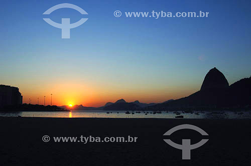  Silhueta do Pão de Açúcar  com sol nascendo - Praia de Botafogo - Rio de Janeiro - RJ - Brasil - obs.:foto digital   é comum chamarmos de Pão de Açúcar o conjunto da formação rochosa que inclui o Morro da Urca e o próprio Morro do Pão de Açúcar (o mais alto dos dois). O conjunto rochoso é Patrimônio Histórico Nacional desde 08-08-1973.  - Rio de Janeiro - Rio de Janeiro - Brasil