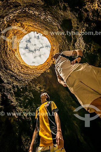  Homens observando o buraco no rochedo da Prainha na freguesia de Alvor  - Concelho de Portimão - Distrito de Faro - Portugal