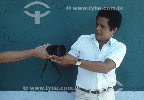  Detalhe do fotógrafo Walter Firmo recebendo máquina fotográfica - década de 80  - Rio de Janeiro - Rio de Janeiro (RJ) - Brasil