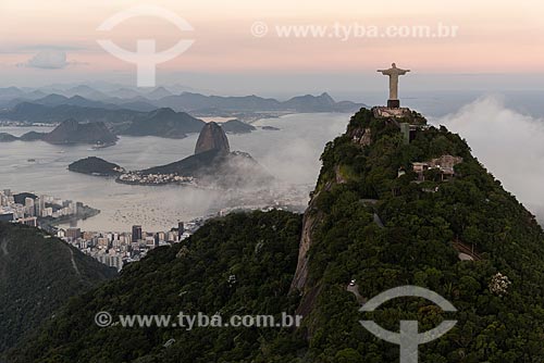  Foto aérea do Cristo Redentor com o Pão de Açúcar ao fundo durante o pôr do sol com nevoeiro  - Rio de Janeiro - Rio de Janeiro (RJ) - Brasil