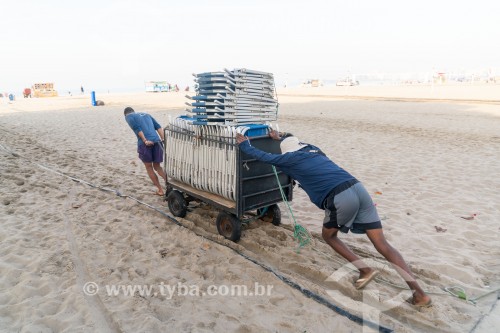 Homens empurrando carrinho de burro-sem-rabo com cadeiras de praia na orla da Praia de Copacabana - Rio de Janeiro - Rio de Janeiro (RJ) - Brasil