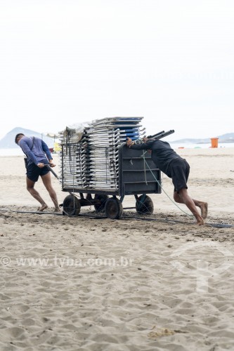 Homens empurrando carrinho de burro-sem-rabo com cadeiras de praia na orla da Praia de Copacabana - Rio de Janeiro - Rio de Janeiro (RJ) - Brasil