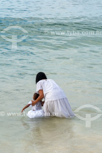 Mulher com criança jogando oferendas para Iemanjá no mar durante a festa no dia da Rainha do Mar - Praia do Arpoador - Rio de Janeiro - Rio de Janeiro (RJ) - Brasil