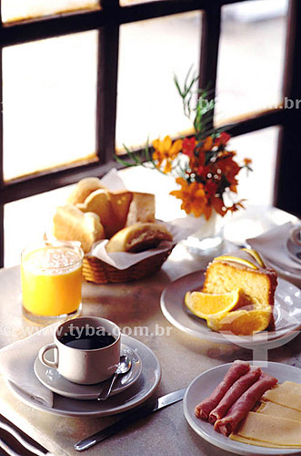  Breakfast - cup of coffee, cake, ham, cheese, orange juice and basket with breads. 