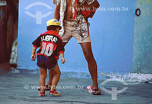  Man and boy (with the shirt of the Flamengo team) playing soccer with a cup - Brazil 