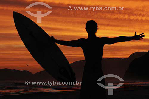  Surfer silhouette holding a surf board with arm wide open 