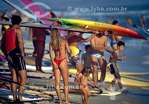  People at the beach and surfers (windsurf) with their boards 