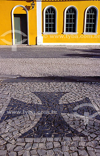  Detail of Architecture - Sidewalk in Portuguese stone with Cruz of Malta, one of the symbols of Portugal, in mosaic in front of a yellow house of windows and door white and green  - Portuguese Colonization - Porto Seguro* - Bahia state - Brazil  * T 