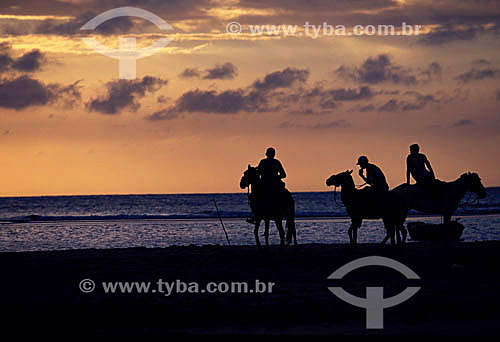  People riding horseback on Jericoacoara Beach at sunset - Ceara state - Brazil 