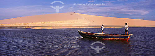  Jericoacoara Beach with men on the boat and dunes in the background - Ceara state - Brazil 
