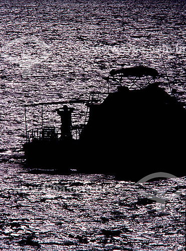  Man`s silhouette on the boat in the sea - Guarapari - Espirito Santo state - Brazil 