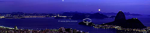  Panoramic view of the moon rising above Sugar Loaf Mountain* at twilight with the city lights of Botafogo Cove in the foreground and the city of Niteroi in the background - Rio de Janeiro city - Rio de Janeiro state - Brazil *Commonly called Sugar L 