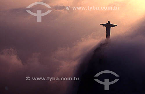  Silhouette of Cristo Redentor (Christ the Redeemer) extending above clouds illuminated by the reflection of the sunset - Rio de Janeiro city - Rio de Janeiro state - Brazil 