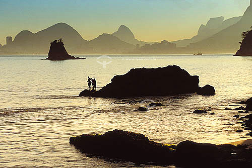  Rocks and fishermen silhouettes in Itapuca beach with Rio de Janeiro city in the background - Niteroi city - Rio de Janeiro state - Brazil 