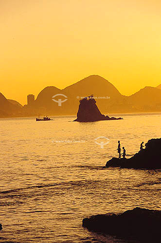  Rocks and fishermen silhouettes in Itapuca beach with Rio de Janeiro city in the background - Niteroi city - Rio de Janeiro state - Brazil 